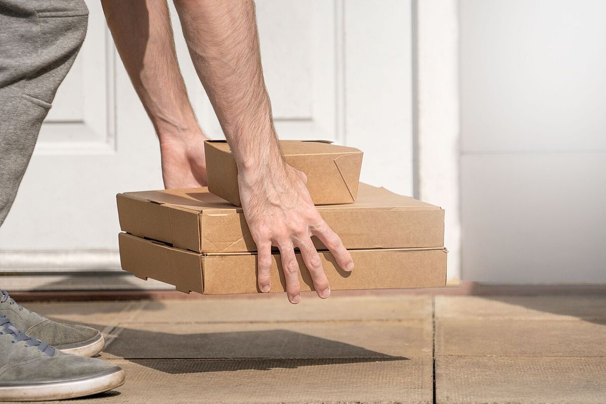 A delivery person setting packages on a doorstep (stock photo)
