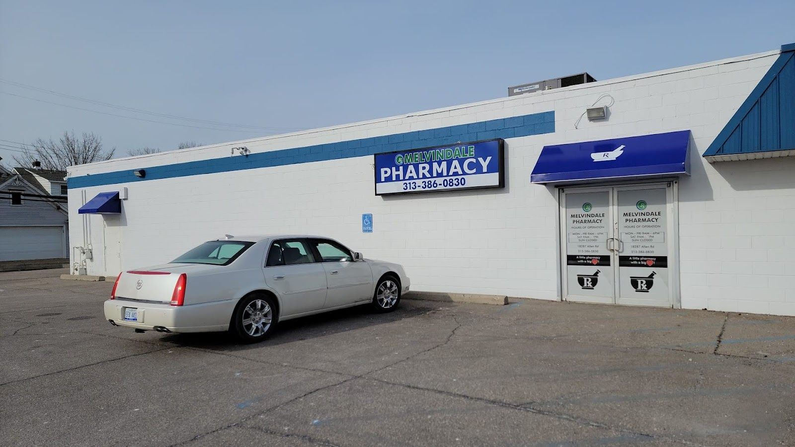 The side of the Melvindale Pharmacy building, with a car parked in the lot